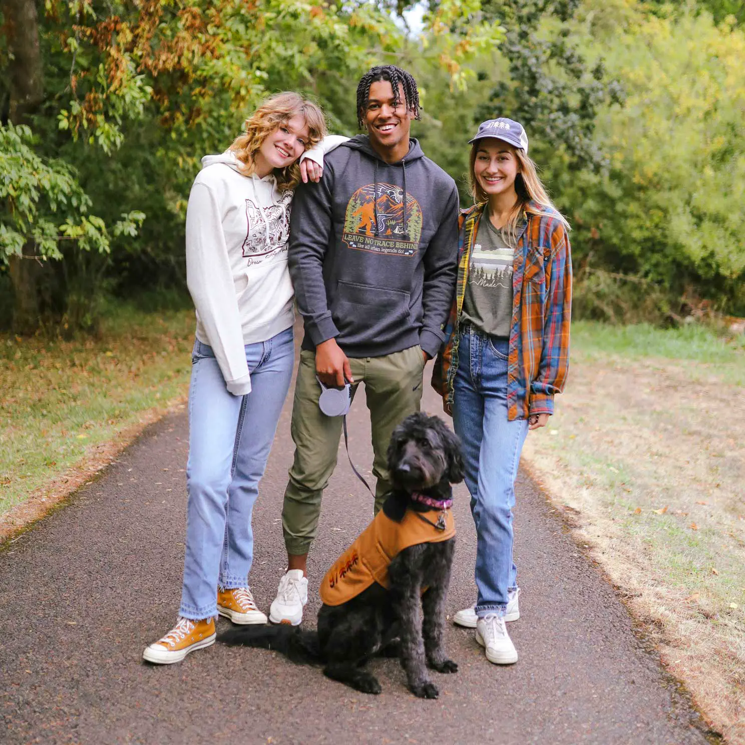 Three people standing on a sidewalk with a dog